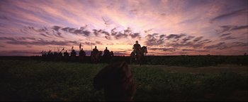 Movie still from “Camelot” (1967), directed by Joshua Logan – A group of people riding horses on a field; Extreme Wide shot, Low angle