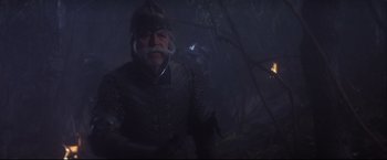 Movie still from “Camelot” (1967), directed by Joshua Logan – An old man wearing a helmet and holding something in his hand; Medium shot, Low angle