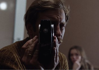 Movie still from “Camera Buff” (1979), directed by Krzysztof Kieslowski – A man taking a picture of himself with a cell phone; Close Up shot, Low angle