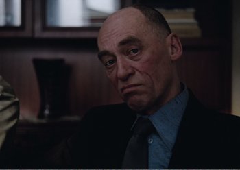 Movie still from “Camera Buff” (1979), directed by Krzysztof Kieslowski – A man in a suit and tie sitting in a room; Close Up shot, Low angle