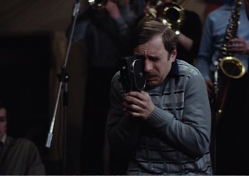 Movie still from “Camera Buff” (1979), directed by Krzysztof Kieslowski – A man holding a camera in front of a group of people; Close Up shot, High angle