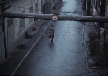 Movie still from “Camera Buff” (1979), directed by Krzysztof Kieslowski – A woman walking down a street in the rain; Wide shot, High angle