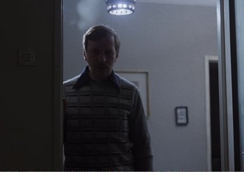 Movie still from “Camera Buff” (1979), directed by Krzysztof Kieslowski – A man standing in front of a mirror in a room; Medium shot, Over the shoulder angle