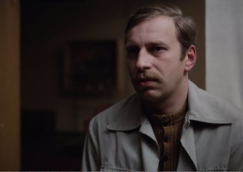 Movie still from “Camera Buff” (1979), directed by Krzysztof Kieslowski – A person wearing a jacket and a tie; Close Up shot, Low angle