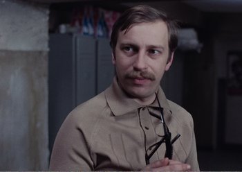 Movie still from “Camera Buff” (1979), directed by Krzysztof Kieslowski – A man in a tan shirt holding a pair of glasses; Close Up shot, Low angle