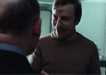 Movie still from “Camera Buff” (1979), directed by Krzysztof Kieslowski – A man in a brown sweater talking to another man in a blue suit; Close Up shot, Over the shoulder angle