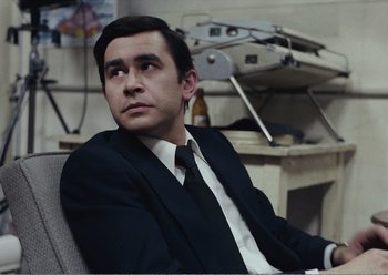 Movie still from “Camera Buff” (1979), directed by Krzysztof Kieslowski – A man in a suit and tie sitting in front of a computer; Medium shot, Low angle