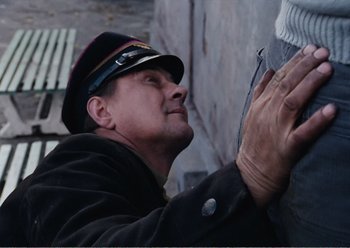 Movie still from “Camera Buff” (1979), directed by Krzysztof Kieslowski – A man wearing a hat touching the side of a wall; Close Up shot, Low angle