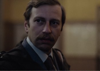 Movie still from “Camera Buff” (1979), directed by Krzysztof Kieslowski – A person wearing a suit and tie; Close Up shot, Over the shoulder angle