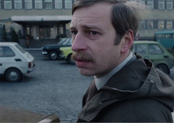 Movie still from “Camera Buff” (1979), directed by Krzysztof Kieslowski – A person wearing a jacket; Close Up shot, Over the shoulder angle