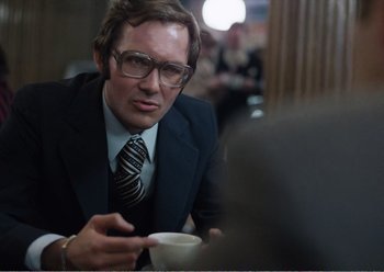 Movie still from “Camera Buff” (1979), directed by Krzysztof Kieslowski – A man in a suit and tie holding a cup of coffee; Medium shot, Over the shoulder angle