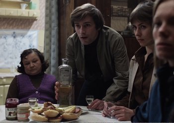 Movie still from “Camera Buff” (1979), directed by Krzysztof Kieslowski – A group of people sitting around a table with food; Medium shot, Over the shoulder angle