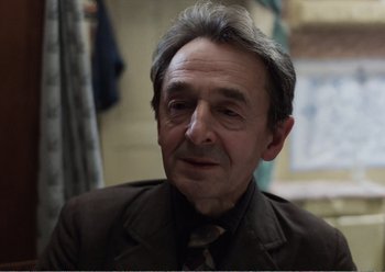 Movie still from “Camera Buff” (1979), directed by Krzysztof Kieslowski – An older man wearing a jacket and a tie; Close Up shot, Over the shoulder angle