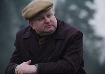 Movie still from “Camera Buff” (1979), directed by Krzysztof Kieslowski – An older man in a brown hat and coat; Close Up shot, Low angle