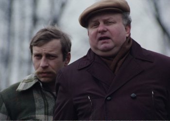 Movie still from “Camera Buff” (1979), directed by Krzysztof Kieslowski – Two men standing next to each other wearing hats; Close Up shot, Over the shoulder angle