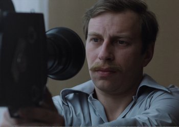 Movie still from “Camera Buff” (1979), directed by Krzysztof Kieslowski – A man is taking a picture of himself with a camera; Close Up shot, Low angle