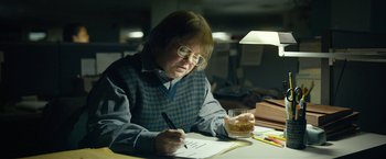 Movie still from “Can You Ever Forgive Me?” (2018), directed by Marielle Heller – An older woman writing on a piece of paper while holding a glass of whiskey; Medium shot, Over the shoulder angle