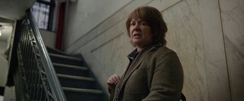 Movie still from “Can You Ever Forgive Me?” (2018), directed by Marielle Heller – A woman standing on the stairs in front of a wall; Medium shot, Over the shoulder angle