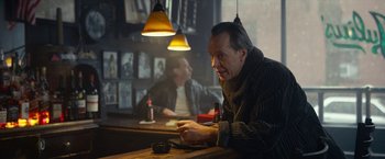 A man sitting at a table in front of a mirror in a bar