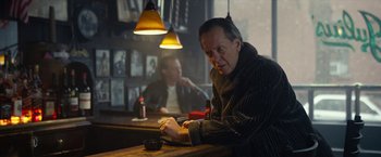 A man sitting at a table in front of a mirror in a bar