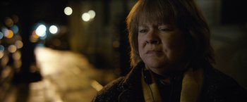 Movie still from “Can You Ever Forgive Me?” (2018), directed by Marielle Heller – An older woman wearing headphones and a jacket; Close Up shot, Over the shoulder angle