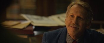 Movie still from “Can You Ever Forgive Me?” (2018), directed by Marielle Heller – An older man smiling for the camera in a suit; Close Up shot, Over the shoulder angle