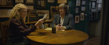 Movie still from “Can You Ever Forgive Me?” (2018), directed by Marielle Heller – A woman sitting at a table holding a piece of paper; Medium shot, High angle