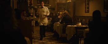 Movie still from “Can You Ever Forgive Me?” (2018), directed by Marielle Heller – A man walking in a restaurant while holding a tray; Wide shot, Over the shoulder angle