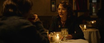 Movie still from “Can You Ever Forgive Me?” (2018), directed by Marielle Heller – A woman sitting at a table with a glass of wine; Close Up shot, Over the shoulder angle