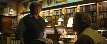 Movie still from “Can You Ever Forgive Me?” (2018), directed by Marielle Heller – A woman is standing in front of a stack of books in a library; Medium shot, Over the shoulder angle