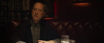 Movie still from “Can You Ever Forgive Me?” (2018), directed by Marielle Heller – A man sitting at a table in front of a glass of water; Close Up shot, Over the shoulder angle