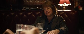 Movie still from “Can You Ever Forgive Me?” (2018), directed by Marielle Heller – A woman sitting at a table with a glass of wine; Close Up shot, Over the shoulder angle