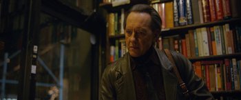 Movie still from “Can You Ever Forgive Me?” (2018), directed by Marielle Heller – An older man wearing a leather jacket in front of a book shelf; Close Up shot, Over the shoulder angle
