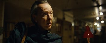 Movie still from “Can You Ever Forgive Me?” (2018), directed by Marielle Heller – An older man wearing a black shirt and a black and blue scarf; Close Up shot, Over the shoulder angle