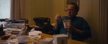 Movie still from “Can You Ever Forgive Me?” (2018), directed by Marielle Heller – A man sitting at a table eating food; Medium shot, Over the shoulder angle
