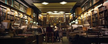 Movie still from “Can You Ever Forgive Me?” (2018), directed by Marielle Heller – A group of people sitting at a table in a library; Wide shot, High angle