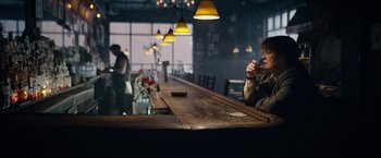 Movie still from “Can You Ever Forgive Me?” (2018), directed by Marielle Heller – A man sitting at a bar drinking a beverage; Wide shot, High angle