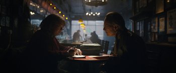 Two people are sitting at a table and one of them is writing