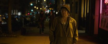 Movie still from “Can You Ever Forgive Me?” (2018), directed by Marielle Heller – A woman wearing a brown coat and a brown hat standing on the sidewalk; Medium shot, Over the shoulder angle