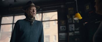 Movie still from “Can You Ever Forgive Me?” (2018), directed by Marielle Heller – An older man wearing a hat and a neck tie; Medium shot, Over the shoulder angle