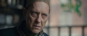 Movie still from “Can You Ever Forgive Me?” (2018), directed by Marielle Heller – An older man with a head scarf looking at the camera; Close Up shot, Over the shoulder angle