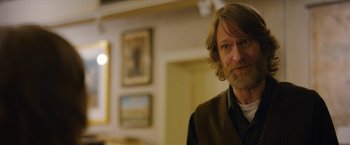 Movie still from “Can You Ever Forgive Me?” (2018), directed by Marielle Heller – A person with long hair and a beard; Close Up shot, Over the shoulder angle