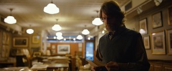 Movie still from “Can You Ever Forgive Me?” (2018), directed by Marielle Heller – A man standing in a room holding a piece of paper; Medium shot, Over the shoulder angle