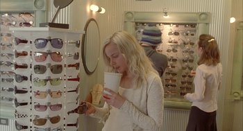 Movie still from “Candy” (2006), directed by Neil Armfield – A woman is holding a drink and looking at a pair of glasses; Medium shot, Over the shoulder angle
