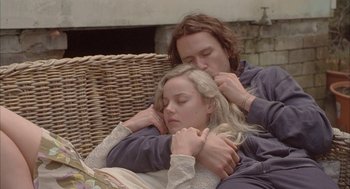 Movie still from “Candy” (2006), directed by Neil Armfield – A man and a woman sitting next to each other on a couch; Medium shot, High angle