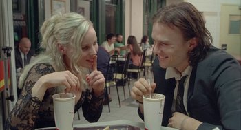 Movie still from “Candy” (2006), directed by Neil Armfield – A man and a woman sitting at a table with drinks; Medium shot, Over the shoulder angle