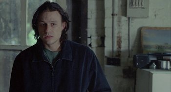 Movie still from “Candy” (2006), directed by Neil Armfield – A man with long black hair is smoking a cigarette; Close Up shot, High angle