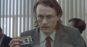 Movie still from “Candy” (2006), directed by Neil Armfield – A man in a suit holding up a card; Close Up shot, Over the shoulder angle