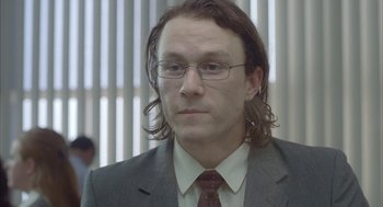 Movie still from “Candy” (2006), directed by Neil Armfield – A person wearing glasses and a suit; Close Up shot, Low angle