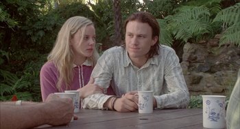 Movie still from “Candy” (2006), directed by Neil Armfield – A man and a woman sitting at a wooden table; Medium shot, Over the shoulder angle